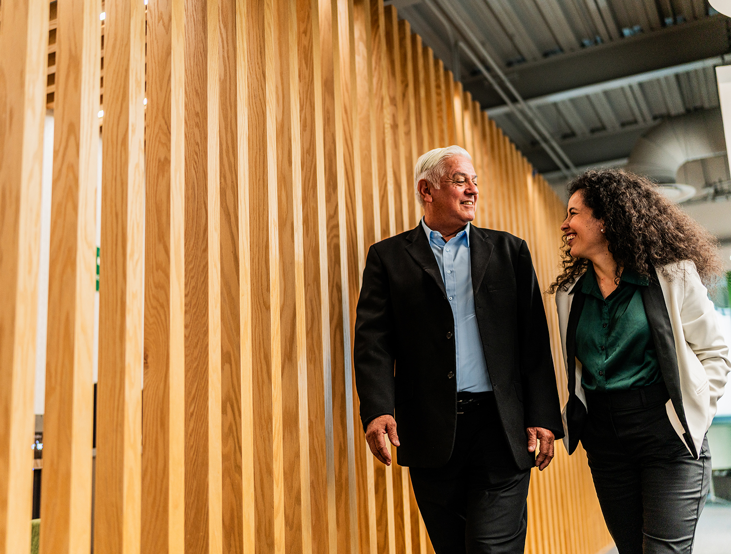 Senior businessman walking and talking with employee at office