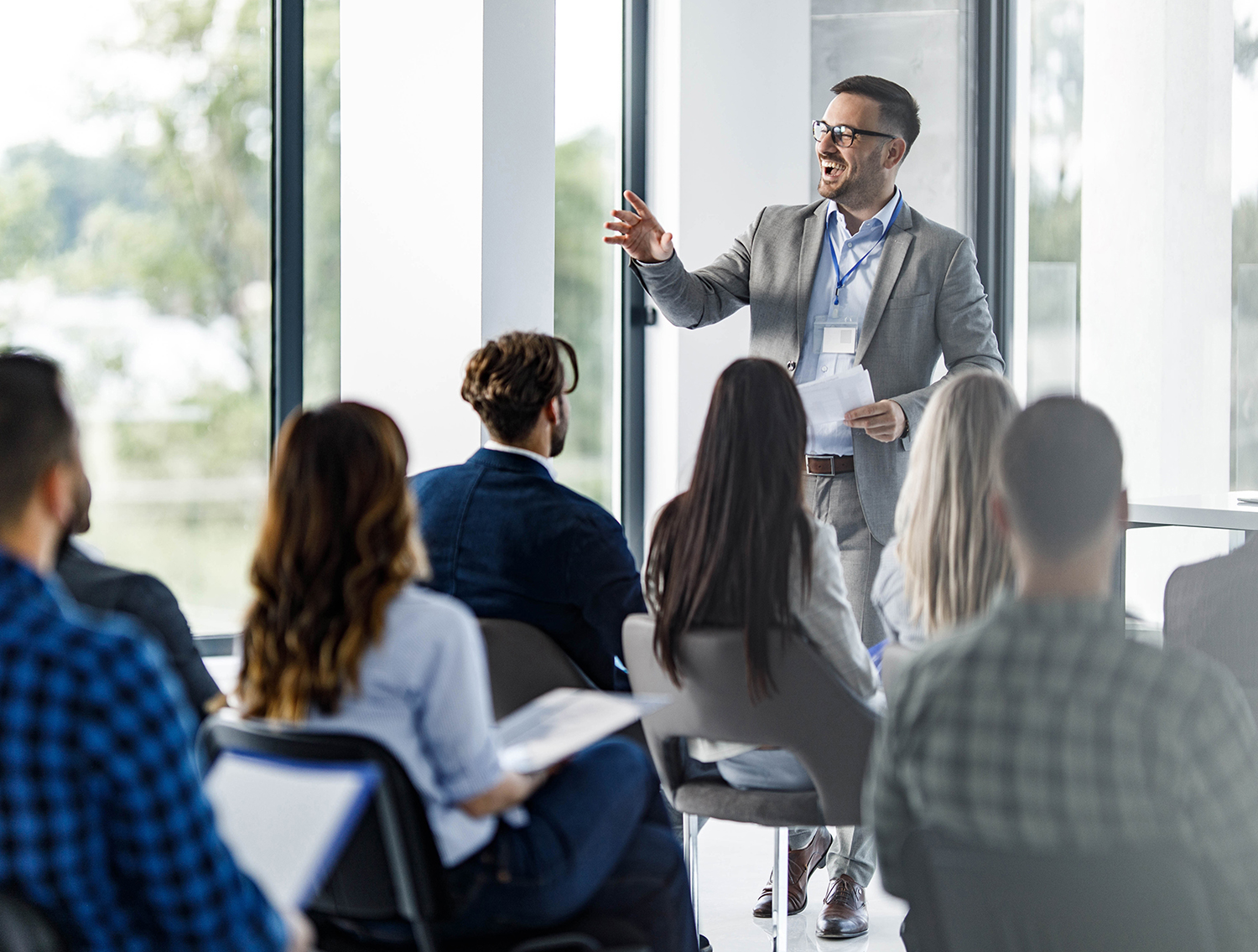 Happy CEO communicating with large group of his colleagues on education event in board room.