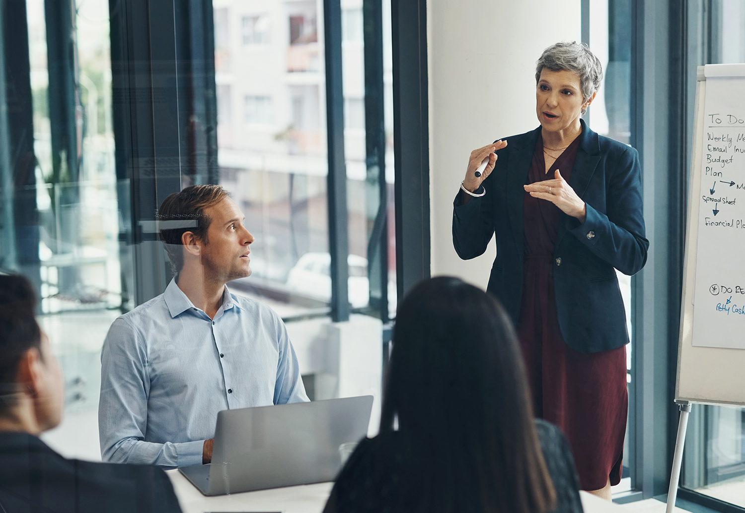 Meeting, whiteboard and senior business woman in boardroom with team for training or coaching. Presentation, planning or strategy with manager and employee group in office for upskill development