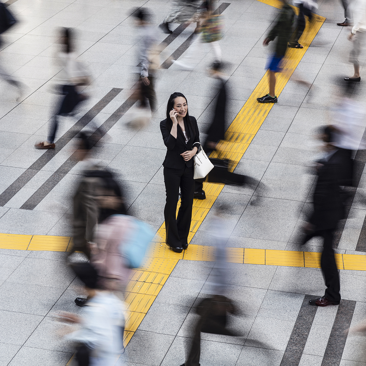 Japanese woman talking on the mobile phone surrounded by commuters walking to work.