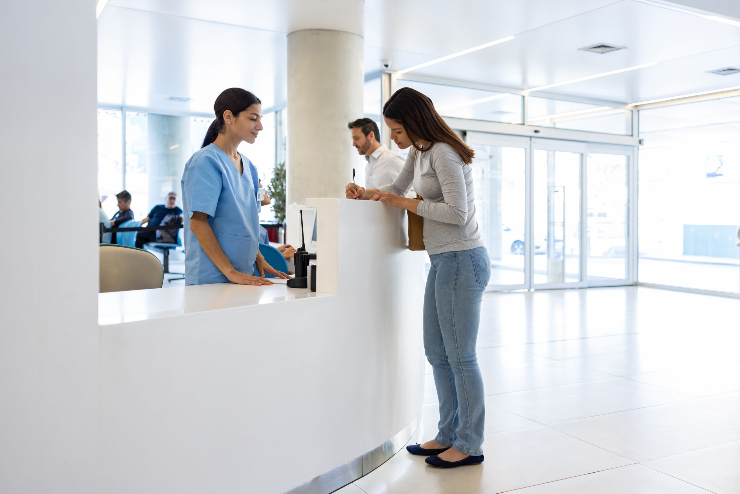Nurse waiting for a patient to fill a form while checking in at the hospital